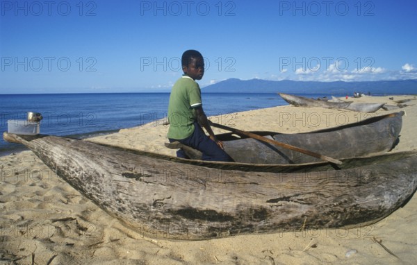 Local boy sitting on a dugout near Kande Beach on Lake Malawi, Malawi, Africa, July 2000, vintage, retro, old, historic
