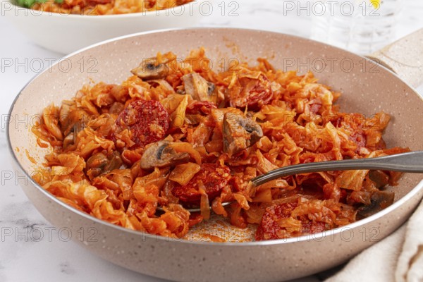 Bigos, Polish dish bigos, on the table, pan with stewed meat, with cabbage, chorizo sausages, mushrooms, homemade, without people