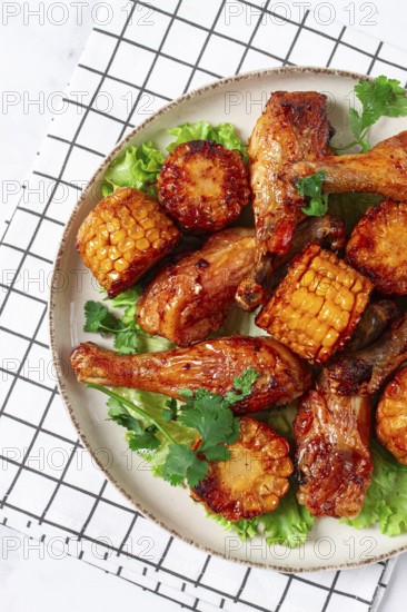 Fried chicken drumsticks, Mexican style, with corn, on a plate, close-up