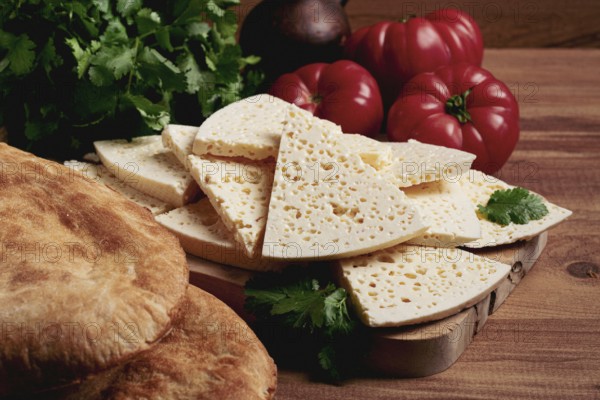 Georgian sliced cheese, on a wooden chopping board, with tomatoes with herbs and lavash, rustic style, Georgian cuisine, no people
