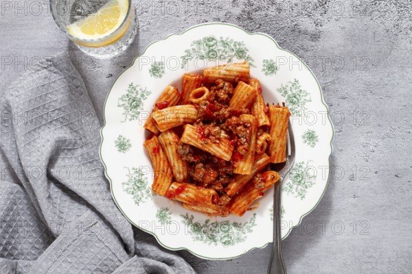 Rigatoni pasta with meat sauce and parmesan cheese on a light table, top view, homemade, no people