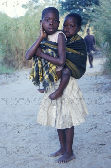 Girl carrying younger sibling at Kande Beach, Malawi, Africa, July 2000, vintage, retro, old, historic