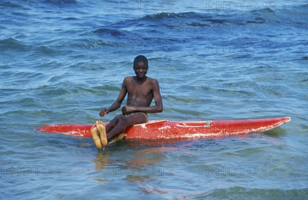 Teenager sitting on a surfboard in Lake Malawi, Kande, Malawi, Africa, July 2000, vintage, retro, old, historic