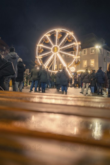 People come together to enjoy an illuminated Ferris wheel at night, Christmas market 2025, Nagold, Black Forest, Calw district, Germany