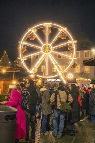 People gather in a Christmas square in front of an illuminated Ferris wheel, Christmas market 2025, Nagold, Black Forest, Calw district, Germany