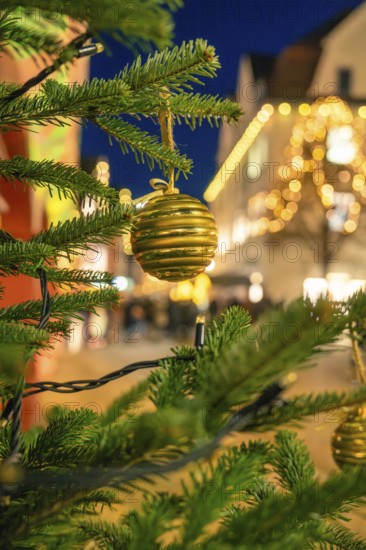 Festive photo of a golden Christmas ball on pine branches with light decoration at night, Christmas market 2025, Nagold, Black Forest, Calw district, Germany