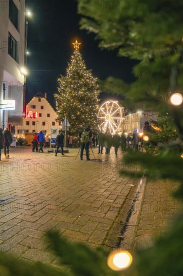 Glowing Christmas tree and Ferris wheel frame a square at night, Christmas market 2025, Nagold, Black Forest, Calw district, Germany