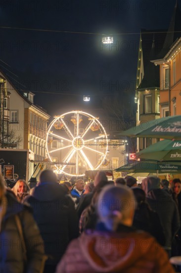 An illuminated Ferris wheel on a night-time Christmas market full of people, Christmas market 2025, Nagold, Black Forest, Calw district, Germany