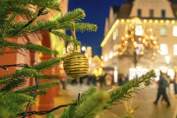 Golden Christmas ball on a pine branch with blurred city lighting in the background, Christmas market 2025, Nagold, Black Forest, Calw district, Germany