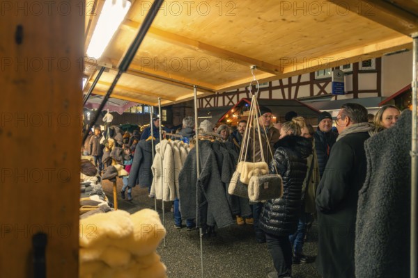 People browse through a range of textiles at a nightly Christmas market, Christmas market 2025, Nagold, Black Forest, Calw district, Germany