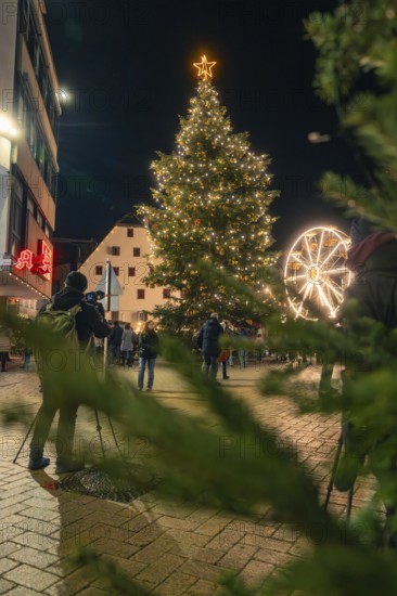Festively illuminated Christmas tree in a square, people and Ferris wheel in the background, Christmas market 2025, Nagold, Black Forest, Calw district, Germany