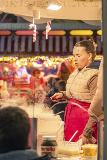 Woman preparing cotton candy at a festive Christmas market, Christmas market 2025, Nagold, Black Forest, Calw district, Germany