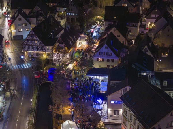 Aerial view of a Christmas market at night with a dense crowd and illuminated half-timbered houses, Aidlingen Christmas market, BÃ¶blingen district, Germany