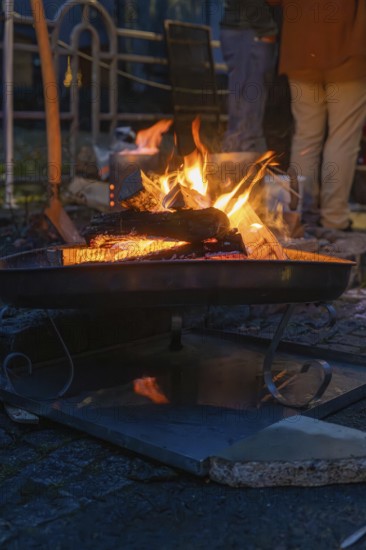 A burning fire provides warmth and comfort on a cool night, Aidlingen Christmas Market, Böblingen District, Germany