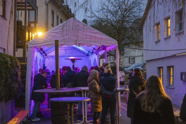 People gather under an illuminated canopy at night, Aidlingen Christmas market, Böblingen district, Germany