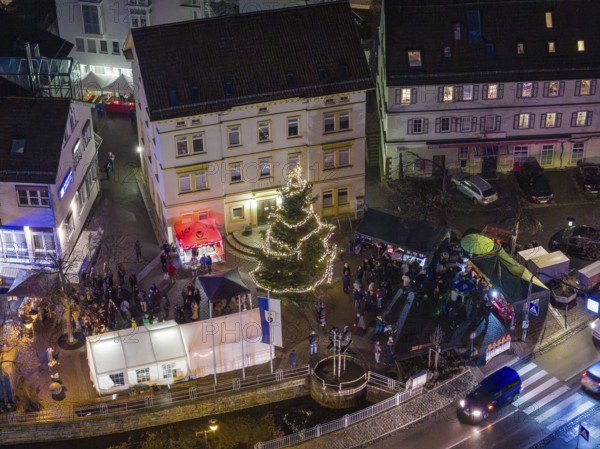 Square with illuminated Christmas tree and people gathered at night, Aidlingen Christmas market, Böblingen district, Germany