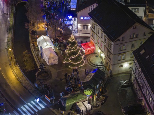 Market scene at night with Christmas tree, festive lights and people near tents, Aidlingen Christmas market, Böblingen district, Germany