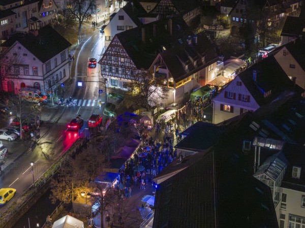 Aerial view of a busy Christmas market at night with illuminated half-timbered houses and crowds of visitors, Aidlingen Christmas market, BÃ¶blingen district, Germany