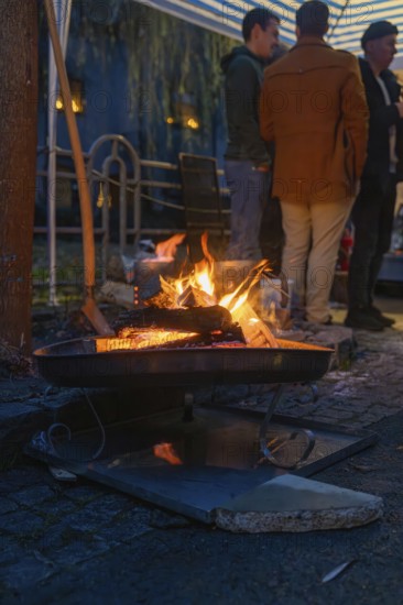 A few people stand next to a warming fireplace at night, Aidlingen Christmas market, Böblingen district, Germany