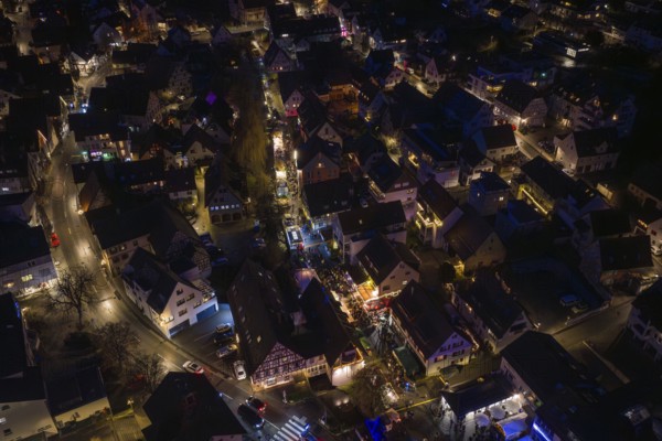 Festively illuminated village at night with lots of people and lights, Aidlingen Christmas market, Böblingen district, Germany