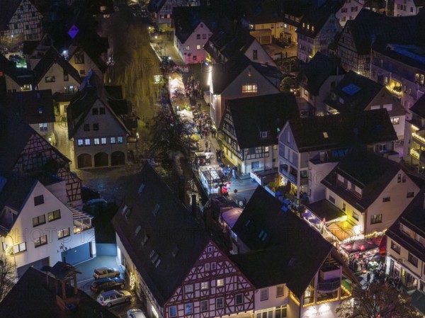 Night view of a village with illuminated half-timbered houses and roads, Aidlingen Christmas market, Böblingen district, Germany