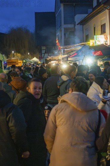Large crowd enjoying the night atmosphere at a busy Christmas market with stalls and lights, Aidlingen Christmas market, Böblingen district, Germany
