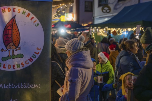 Visitors stroll through a brightly lit and festively decorated Christmas market with children, Aidlingen Christmas market, Böblingen district, Germany