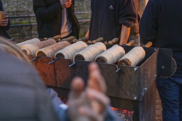 Several trdelnÃ­k pastries prepared on a market stand at night, Aidlingen Christmas market, Böblingen district, Germany