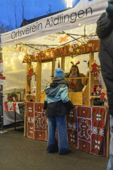Christmas market stand with glowing decorations and people in front of it, Aidlingen Christmas market, Böblingen district, Germany