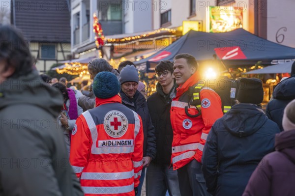 Red Cross members in uniforms happily interact at a well-attended Christmas market, Aidlingen Christmas market, Böblingen district, Germany