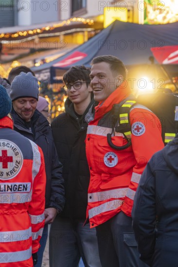 Red Cross paramedics stand at a Christmas market, engaged and friendly amidst the crowd, Aidlingen Christmas market, Böblingen district, Germany