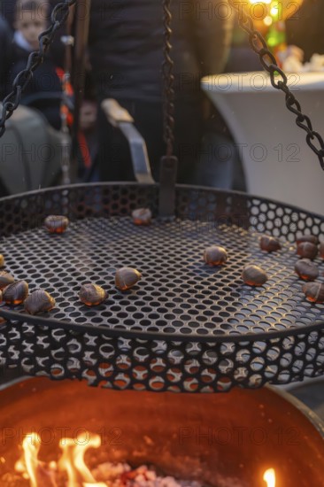 Roasting chestnuts over a fireplace at dusk, Aidlingen Christmas Market, Böblingen District, Germany