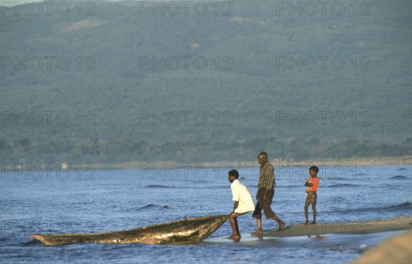 Men letting dugout into water, boy, Lake Malawi, Kande, Malawi, Africa, July 2000, vintage, retro, old, historical