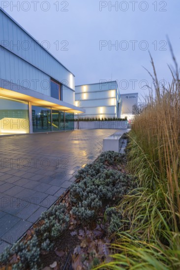 Illuminated, modern building in the evening with glass faÃ§ade and green plants in the foreground, Open Horizons exhibition, Schauwerk Sindelfingen, Böblingen district, Germany