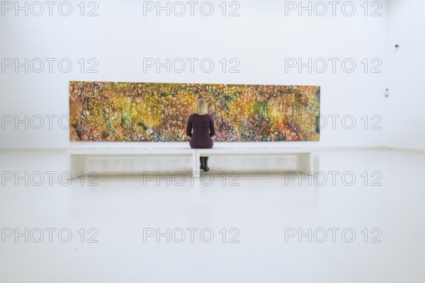 Woman sitting on bench looking at large, colorful, abstract work of art, Open Horizons exhibition, Schauwerk Sindelfingen, Böblingen district, Germany