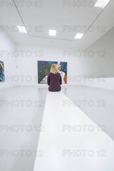 A woman sitting in a bright art gallery in front of an expressive painting, Open Horizons exhibition, Schauwerk Sindelfingen, BÃ¶blingen district, Germany