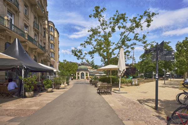 Square, historic building, residential building, outdoor area, restaurant palast-hotel, signpost, pavilion Kochbrunnen pavilion, footpath, park, trees, paths, pedestrians and visitors as a secondary motif, blue sky, cumulus clouds, cirrus clouds, Kochbrunnenplatz, Wiesbaden, state capital, district-free city, Hesse, Germany