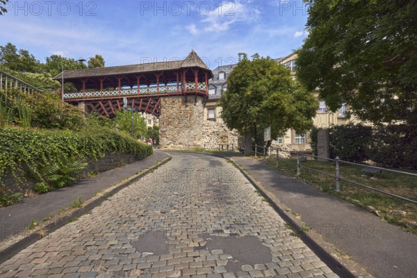 Heidenmauer, historicizing city gate Römertor, city fortification, lantern, metal fence, trees, bushes, cobblestone road, blue sky, cumulus clouds, cirrus clouds, street Am Römertor, Wiesbaden, state capital, district-free city, Hesse, Germany