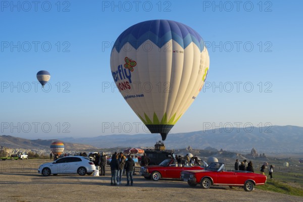 People and cars gather around a large balloon ready to launch, hot air balloons, Göreme National Park, Göreme Tarihî Millî ParkÄ±, Nevsehir Province, NevÅŸehir, Cappadocia, Cappadocia, Central Anatolia, Turkey