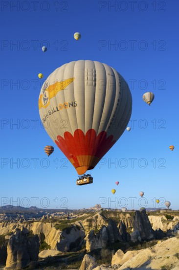A large colorful balloon with decoration floats over a picturesque rocky landscape, hot air balloons, Göreme National Park, Göreme Tarihî Millî ParkÄ±, Nevsehir Province, NevÅŸehir, Cappadocia, Cappadocia, Central Anatolia, Turkey
