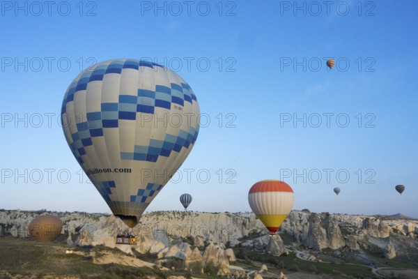 Hot air balloons of various colors float over a picturesque landscape and stand out against the blue sky, Göreme National Park, Göreme Tarihî Millî ParkÄ±, Nevsehir Province, NevÅŸehir, Cappadocia, Cappadocia, Central Anatolia, Turkey