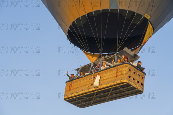 A hot-air balloon basket full of people floats in the warm morning light, symbolizing freedom and the spirit of adventure, Göreme Tarihî Millî ParkÄ±, Nevsehir Province, Nevsehir, Cappadocia, Cappadocia, Central Anatolia, Turkey