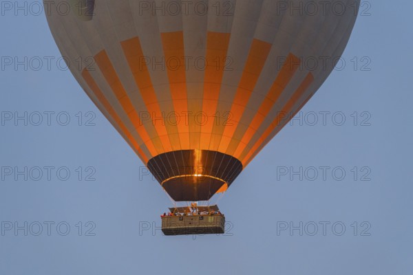 Close-up of glowing hot air balloon with basket and flame against the morning sky, Göreme Tarihî Millî Park, Nevsehir Province, Nevsehir, Cappadocia, Capadocia, Cappadocia, Central Anatolia, Turkey