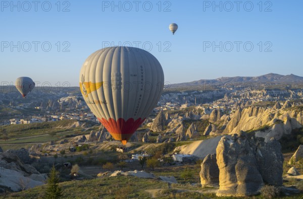 Hot air balloons float over a rocky landscape at sunrise in Capadocia, Göreme National Park, Göreme Tarihî Millî ParkÄ±, Nevsehir Province, Nevsehir, Cappadocia, Cappadocia, Central Anatolia, Turkey