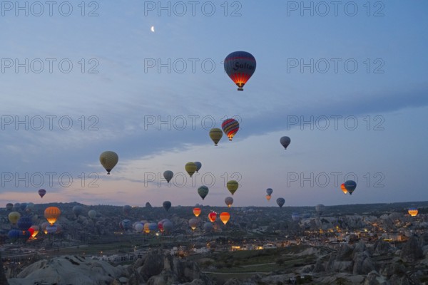 Many hot air balloons float at dusk over the picturesque landscape of Cappadocia, Göreme National Park, Göreme Tarihî Millî ParkÄ±, Nevsehir Province, NevÅŸehir, Cappadocia, Cappadocia, Central Anatolia, Turkey