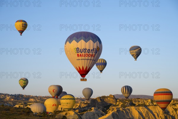 Many colorful hot air balloons rise over rocks early in the morning, Göreme National Park, Göreme Tarihî Millî Park, Nevsehir Province, Nevsehir, Cappadocia, Cappadocia, Central Anatolia, Turkey