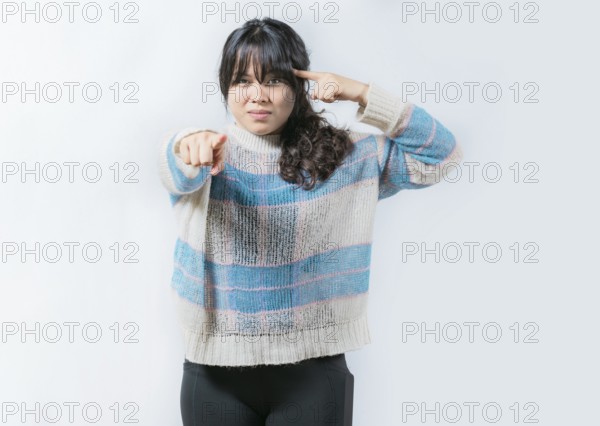 Annoyed bossy woman twirling finger to temple pointing finger at camera