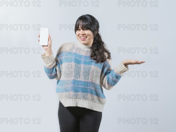 Smiling asian girl showing phone screen isolated. Beautiful asian young woman showing an advertisement on phone screen