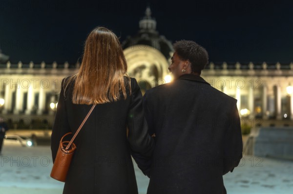 Two women holding arms, enjoying an evening stroll together while exploring the illuminated city streets of paris, showcasing friendship, togetherness, and urban lifestyle