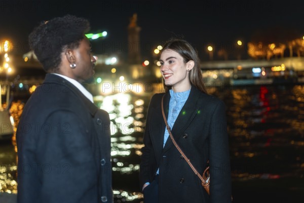 Young diverse couple standing by paris river at night, enjoying an intimate conversation during a romantic date, with city lights reflecting in the water creating a bokeh background